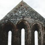 a stone building with three arched windows and a sky background