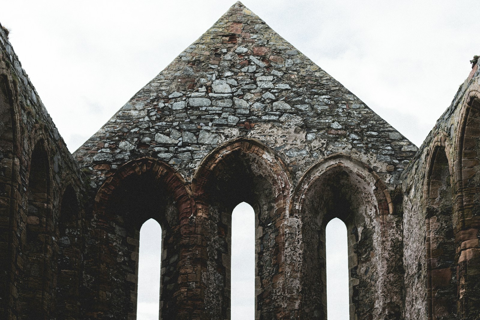 a stone building with three arched windows and a sky background